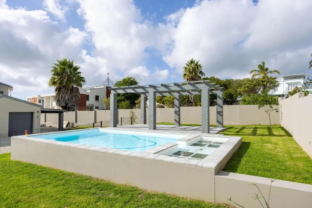 Modern swimming pool with pergola and manicured garden surroundings