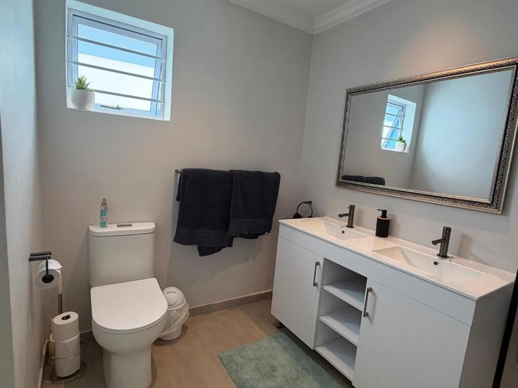 Modern bathroom with dual vanity sinks, toilet, and large mirror