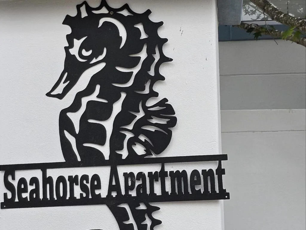 Black seahorse sign for Seahorse Apartment on white wall
