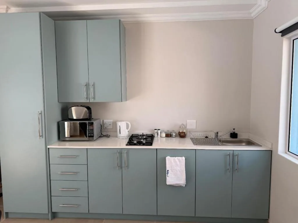 Modern kitchen with gray cabinetry, gas cooktop, microwave, and sink