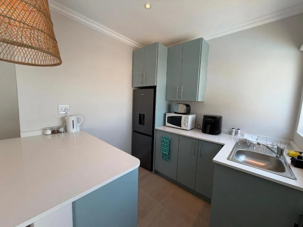 Modern kitchen with grey cabinetry, black refrigerator, and stainless steel sink