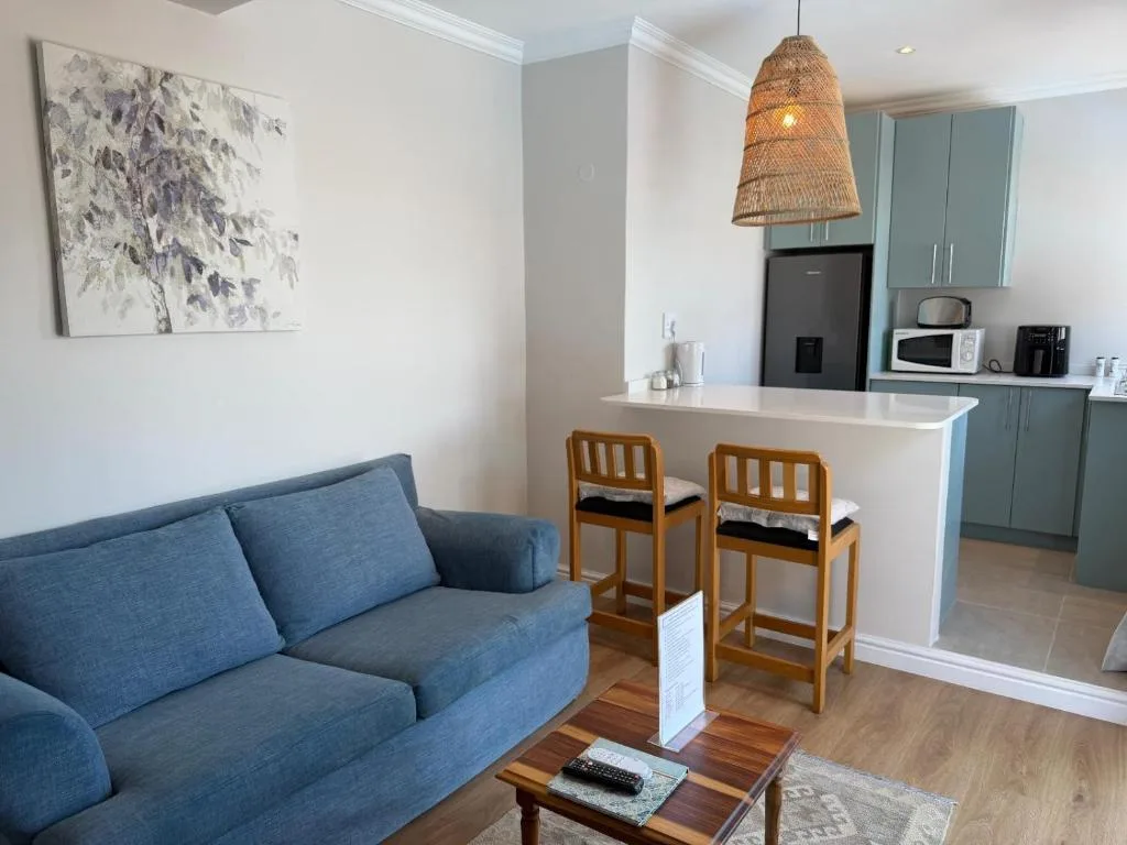 Open-plan lounge with blue sofa, kitchen island, and dining counter seating