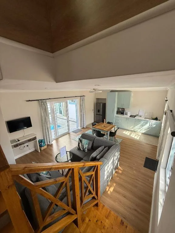 Open-plan lounge with gray sofa, wooden dining table, and TV area