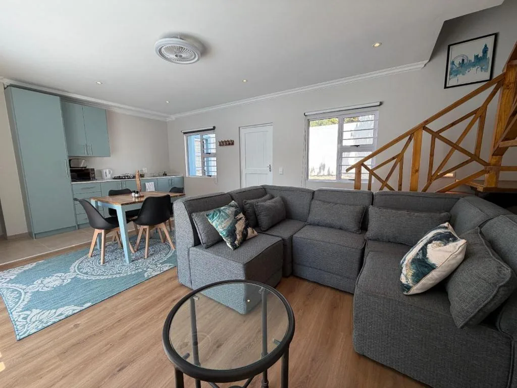 Spacious open-plan lounge with grey sectional sofa and dining area