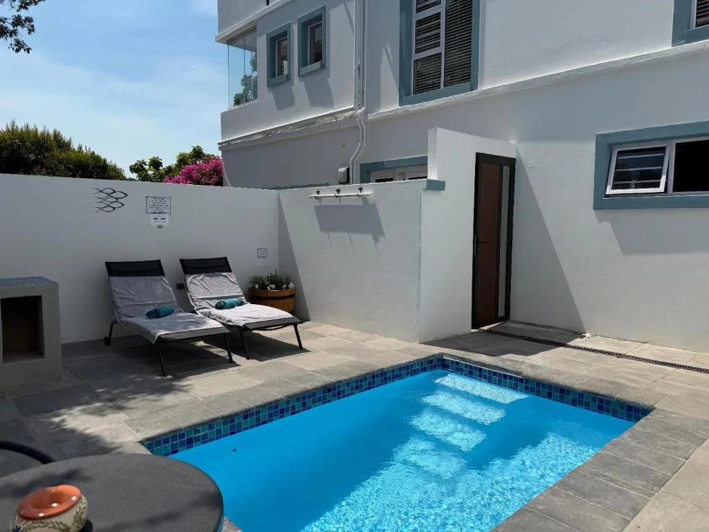 Bright blue swimming pool with sun loungers on surrounding paved deck