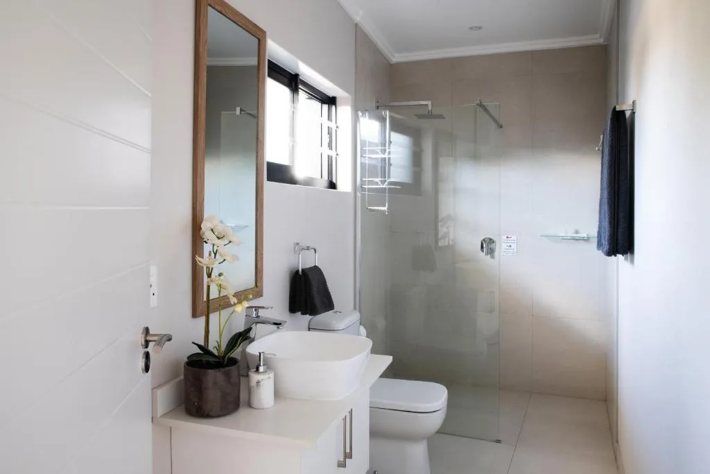 Modern bathroom with white vanity, mirror, toilet, and glass shower enclosure