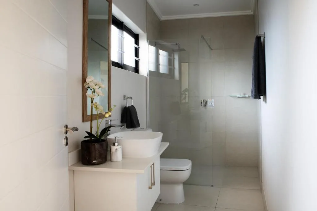 Modern bathroom with white vanity, round sink, toilet, and walk-in shower