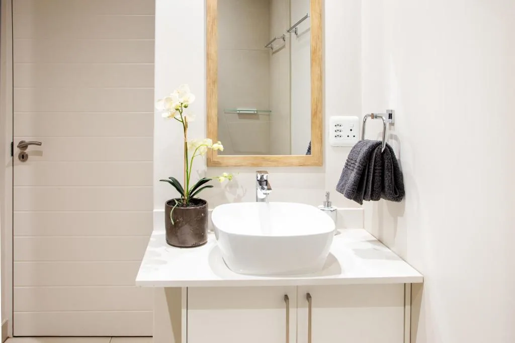 Modern bathroom vanity with white round basin and wooden framed mirror