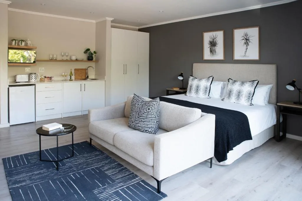 Modern bedroom with queen bed, upholstered headboard, and integrated kitchenette