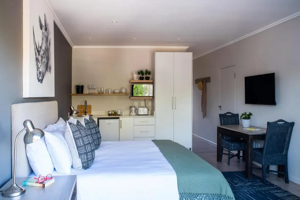 Modern bedroom with bed, kitchenette, desk area, and mounted television