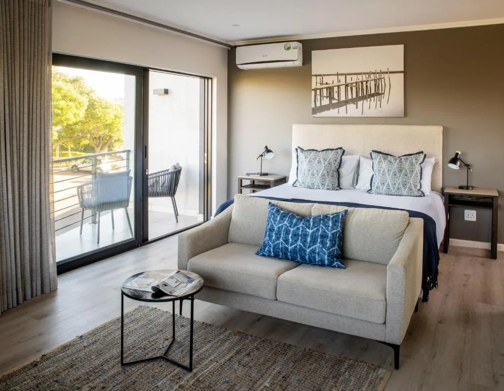 Modern bedroom with bed, sofa, and sliding doors opening to deck