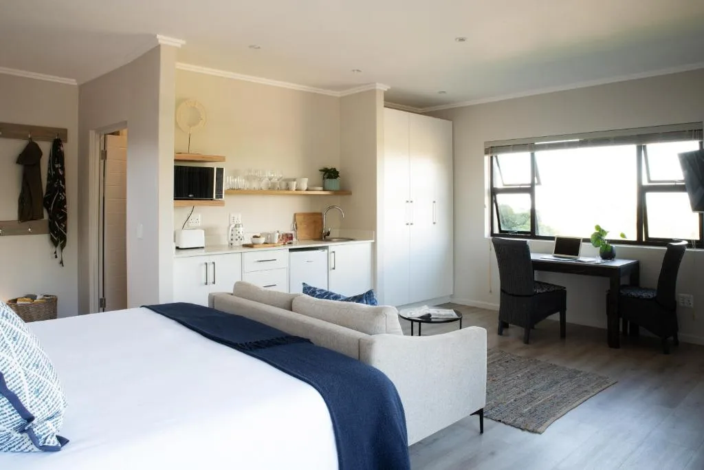 Modern bedroom with bed, kitchenette, lounge area and work desk