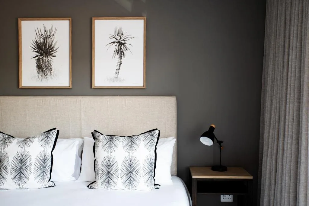 Bed with patterned pillows and framed botanical palm art above