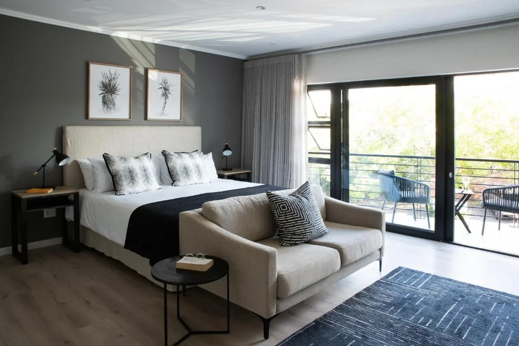 Modern bedroom with bed, seating area, and balcony doors overlooking garden
