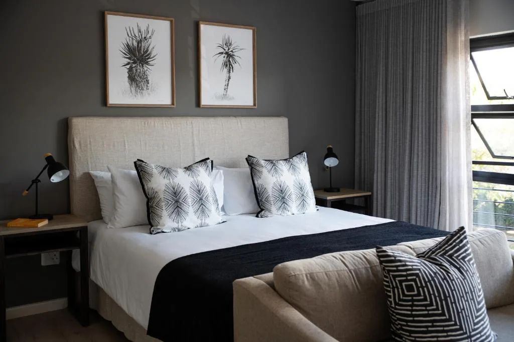 Modern bedroom with queen bed, palm-print pillows, and botanical wall art