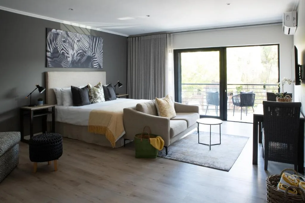 Modern bedroom with king bed, lounge seating, and ocean view balcony access
