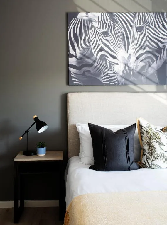 Modern bedroom with bed, black nightstand, and zebra artwork on wall