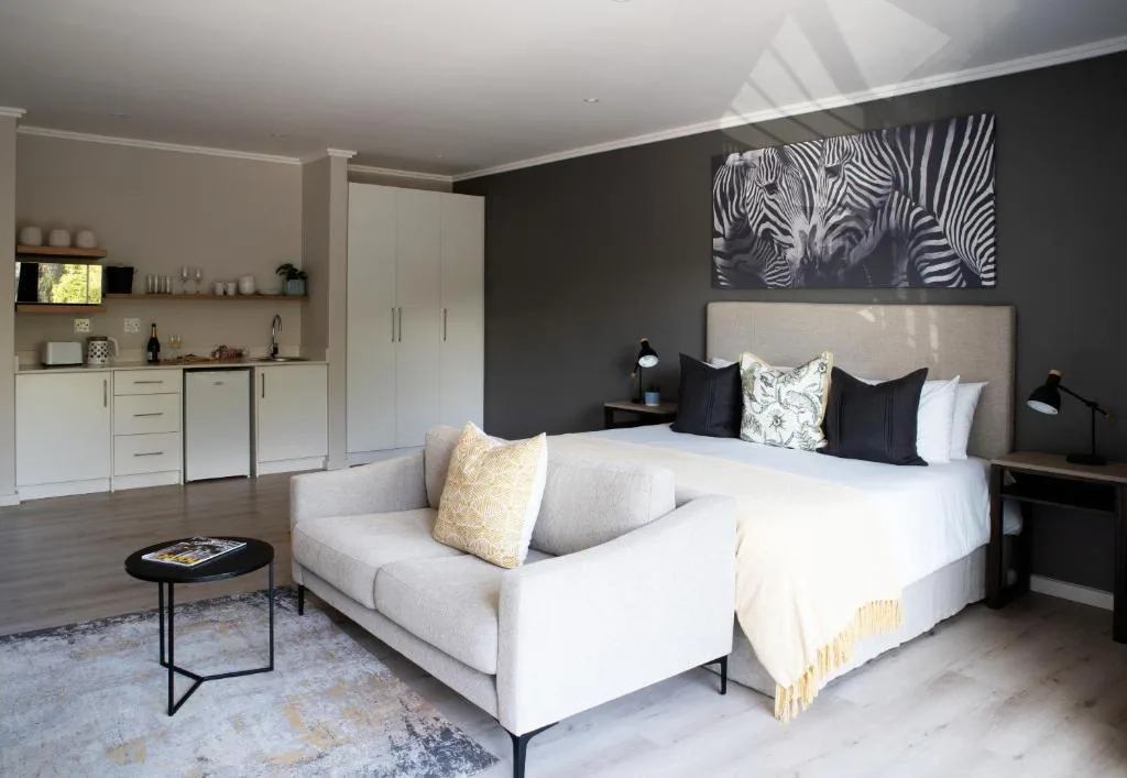 Modern bedroom with double bed, seating area, and integrated kitchenette
