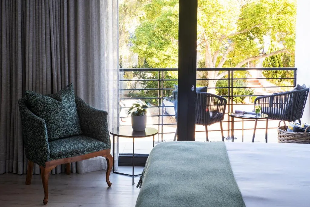 Bedroom with bed, armchair, and private deck with tree views