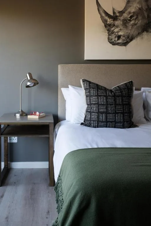 Modern bedroom with bed, patterned pillow, green throw, and bedside lamp