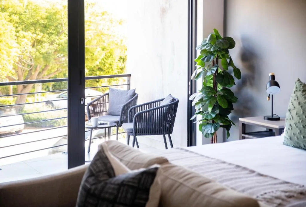 Bright bedroom with bed, sliding doors opening to deck with seating and trees