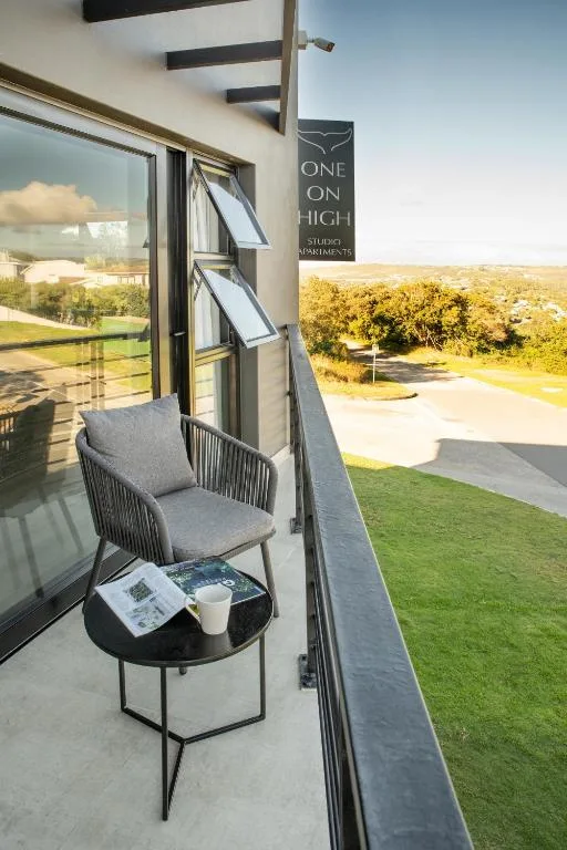 Modern balcony with comfortable seating overlooking manicured gardens and distant fields