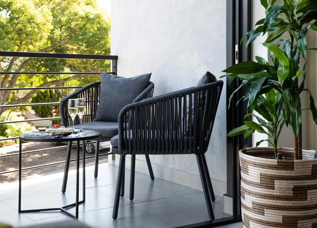 Modern outdoor deck with black woven chairs, small table, and potted plants