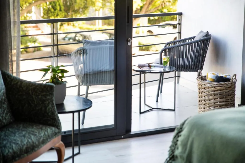 Modern balcony with woven chairs, potted plants, and garden views