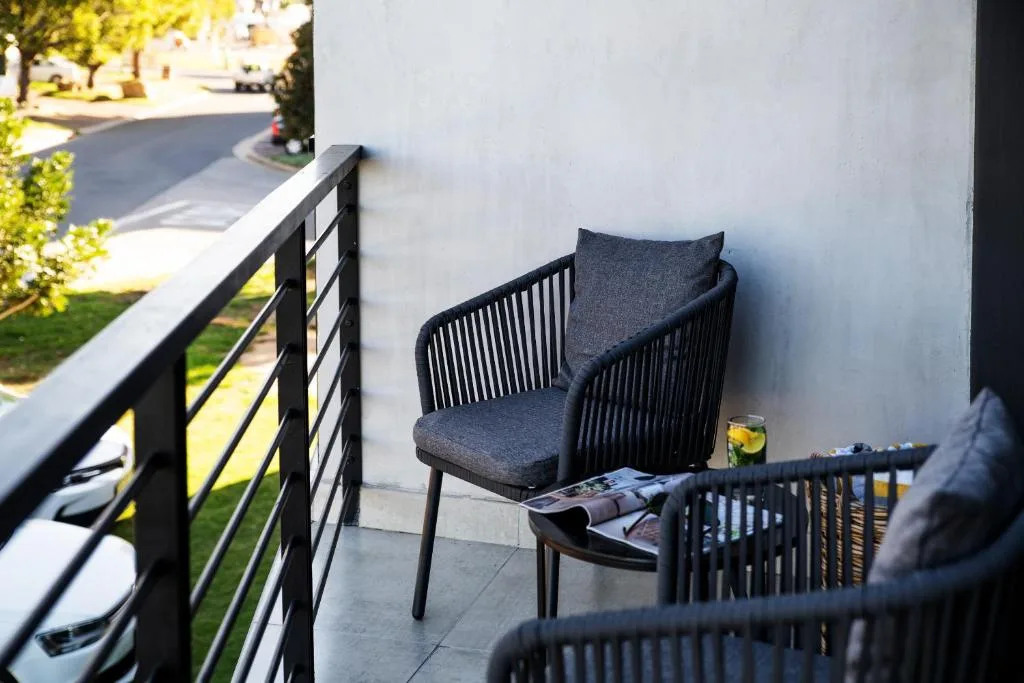 Modern balcony with black outdoor chair and garden views