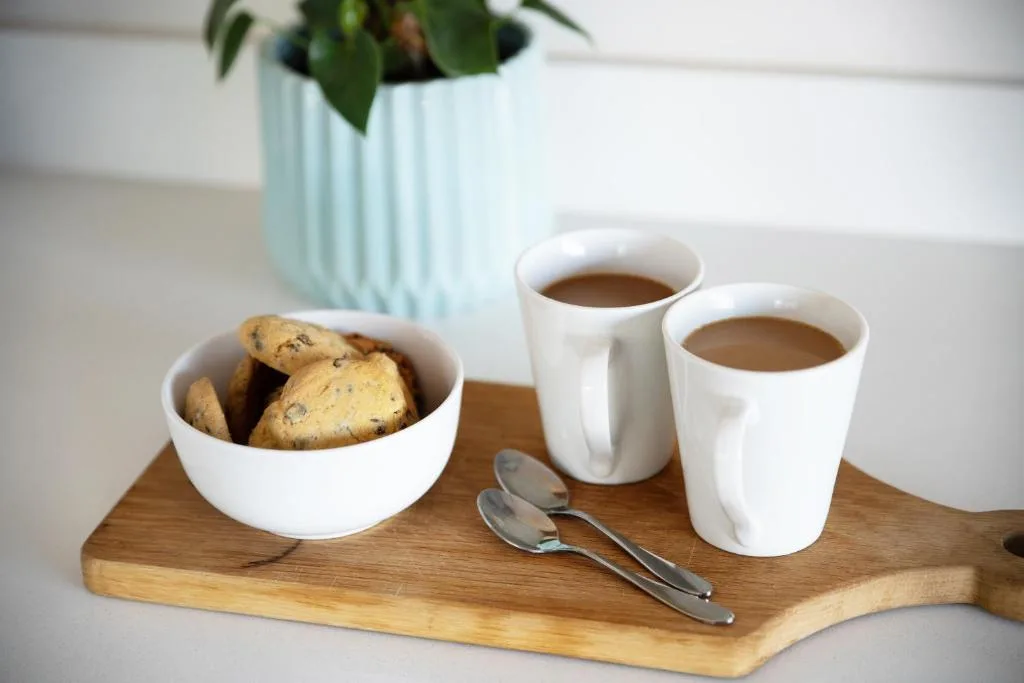 Coffee service with cookies, potted plant on wooden board