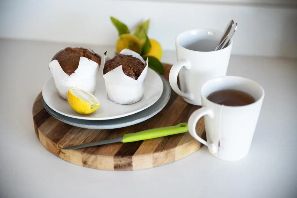 Chocolate muffins with coffee cups and fresh lemons on wooden board