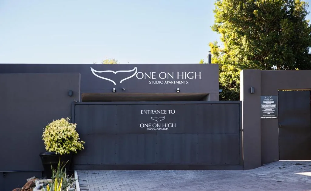 Modern dark facade with One on High Studio Apartments entrance and signage