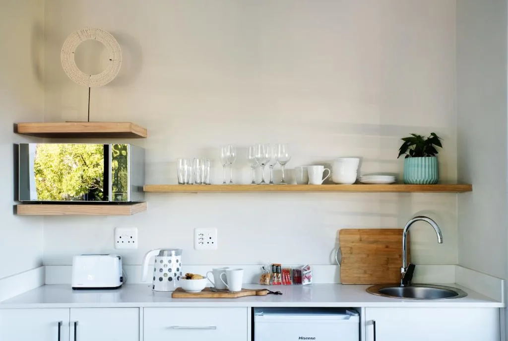 Modern kitchen with white cabinetry, wooden shelves, and stainless steel sink
