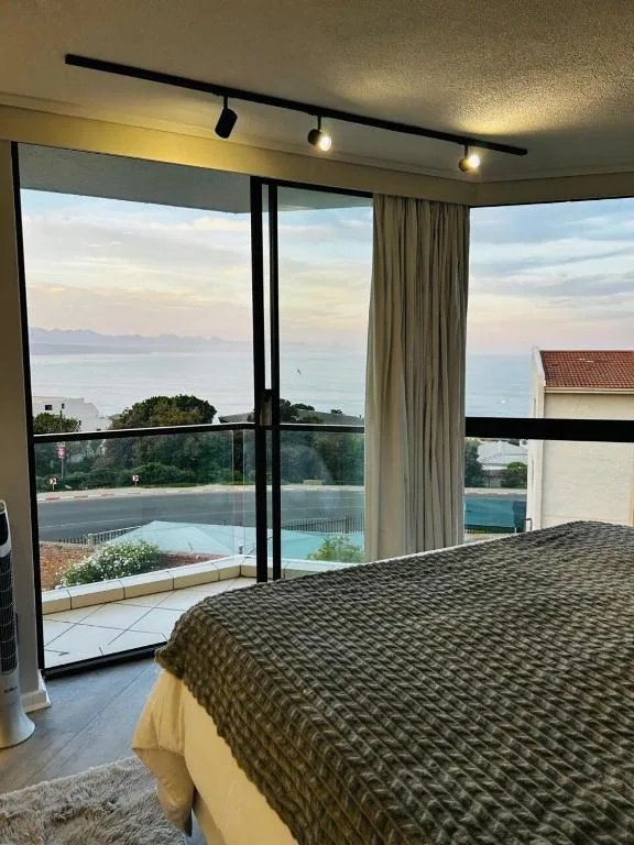 Bedroom with ocean view through large sliding glass doors and pool below