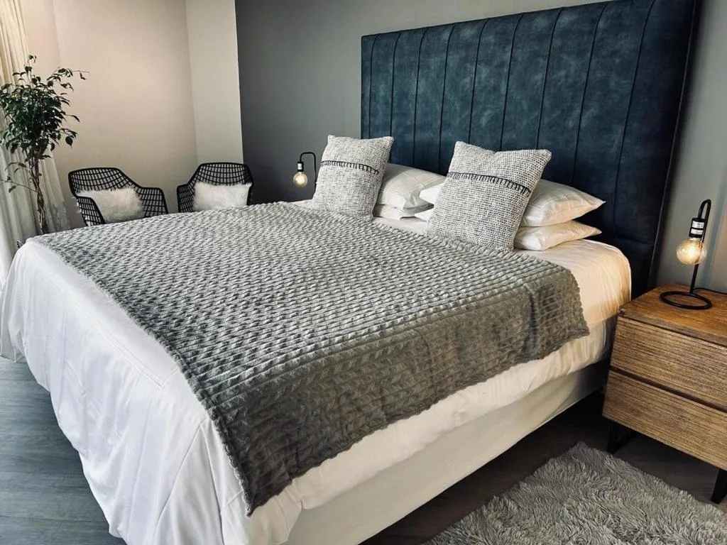 Modern bedroom with upholstered headboard, layered bedding, and pendant lighting
