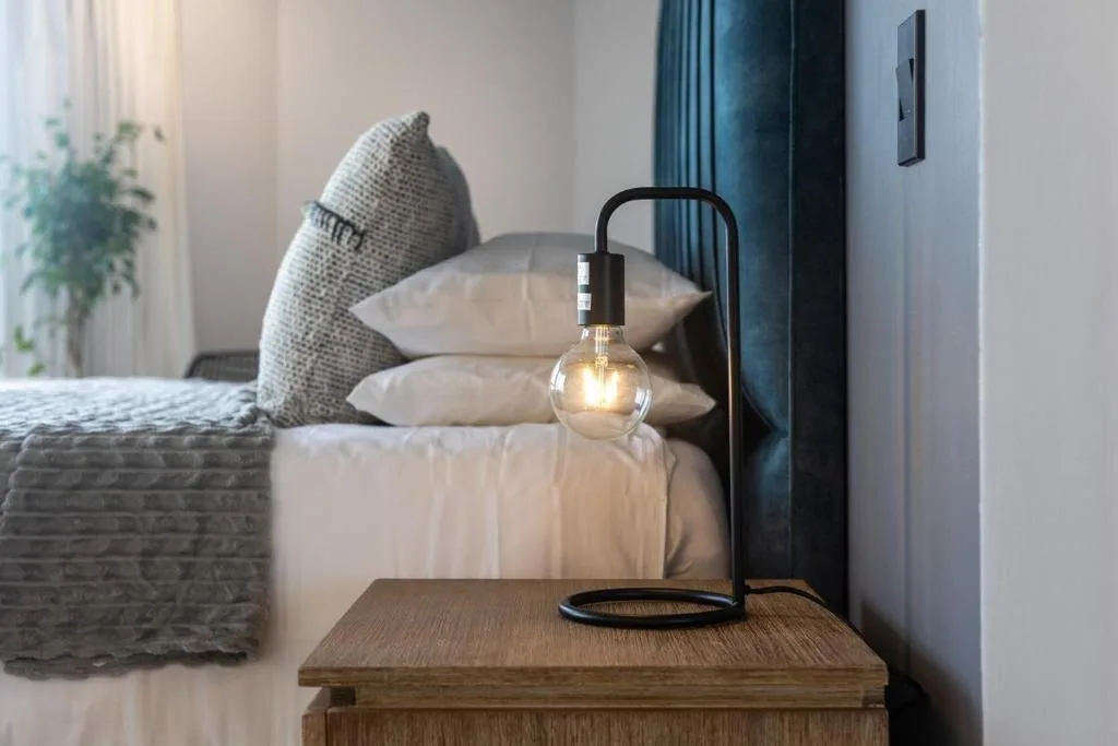 Modern bedroom with bed, decorative lamp, and neutral bedding tones