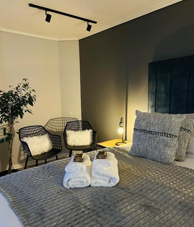 Modern bedroom with bed, seating area, potted plant, and welcoming amenities