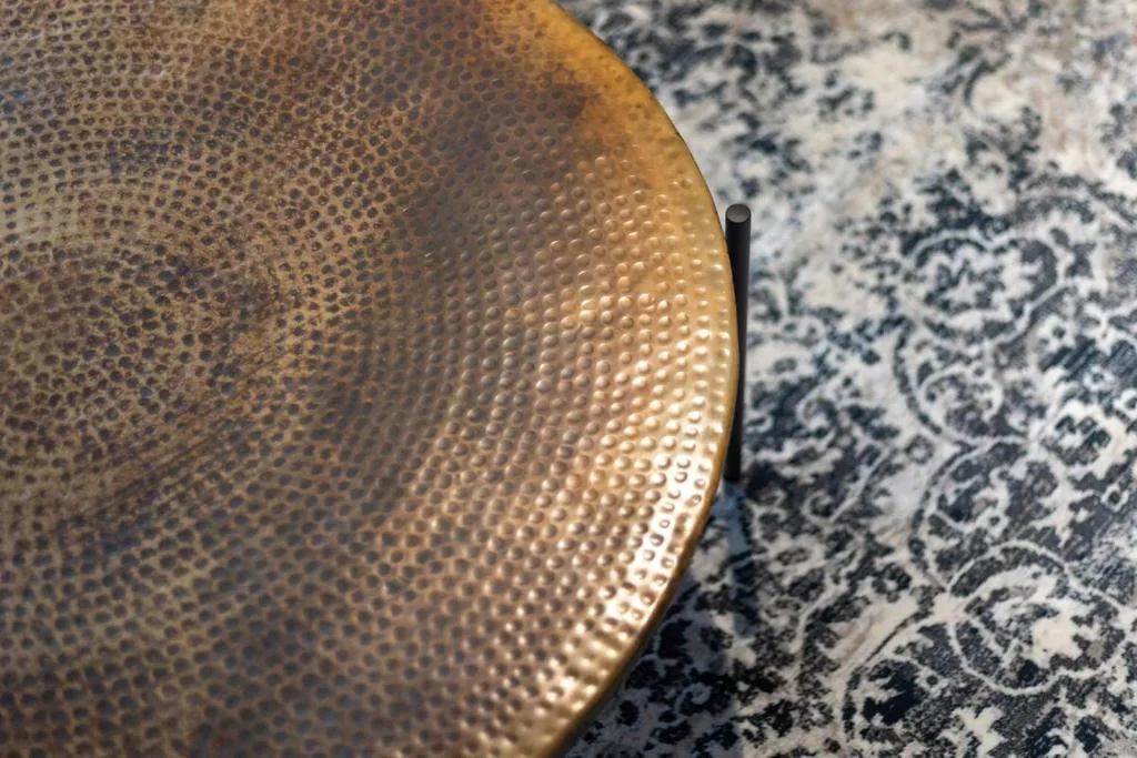 Close-up of decorative hammered brass bowl on patterned rug