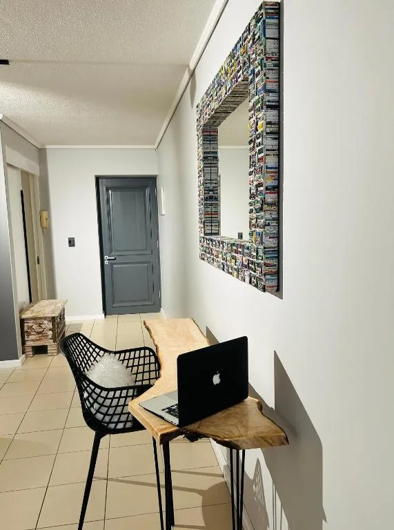 Workspace with laptop at wooden desk and black chair in hallway