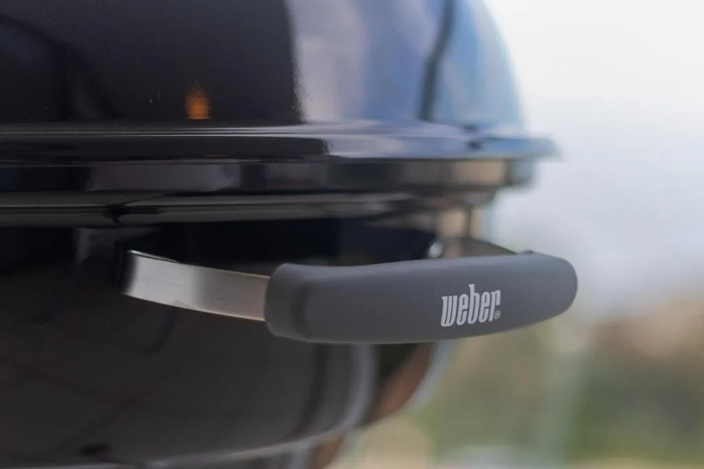 Close-up of Weber braai grill handle with blurred outdoor background