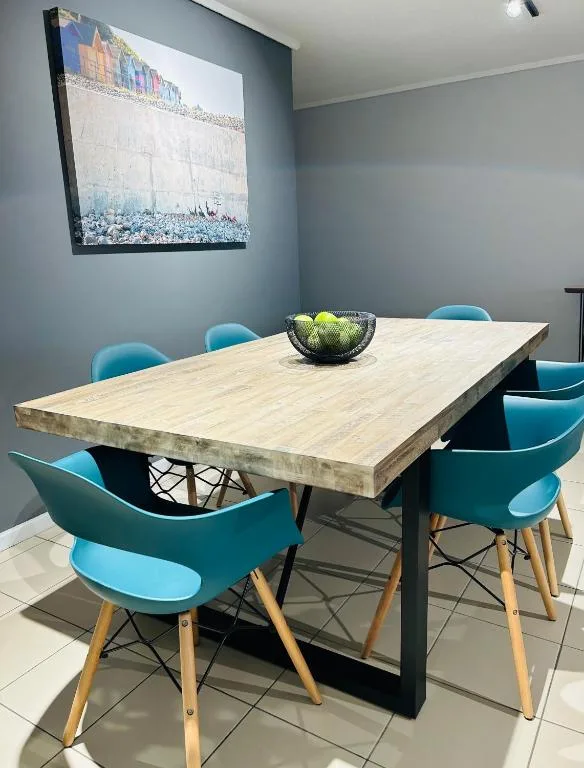 Modern dining table with turquoise chairs and colorful beach artwork