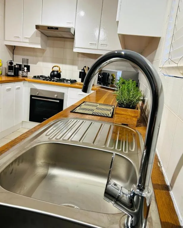 Modern kitchen with stainless steel sink, black tap, white cabinetry and wooden countertops