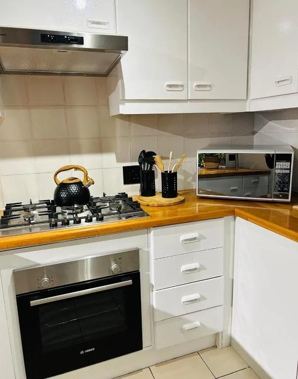 Modern kitchen with white cabinetry, wooden countertop, gas cooktop, and microwave