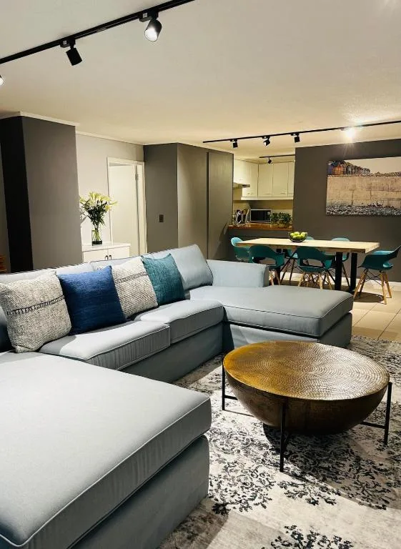 Modern lounge with white sectional sofa, blue cushions, brass coffee table