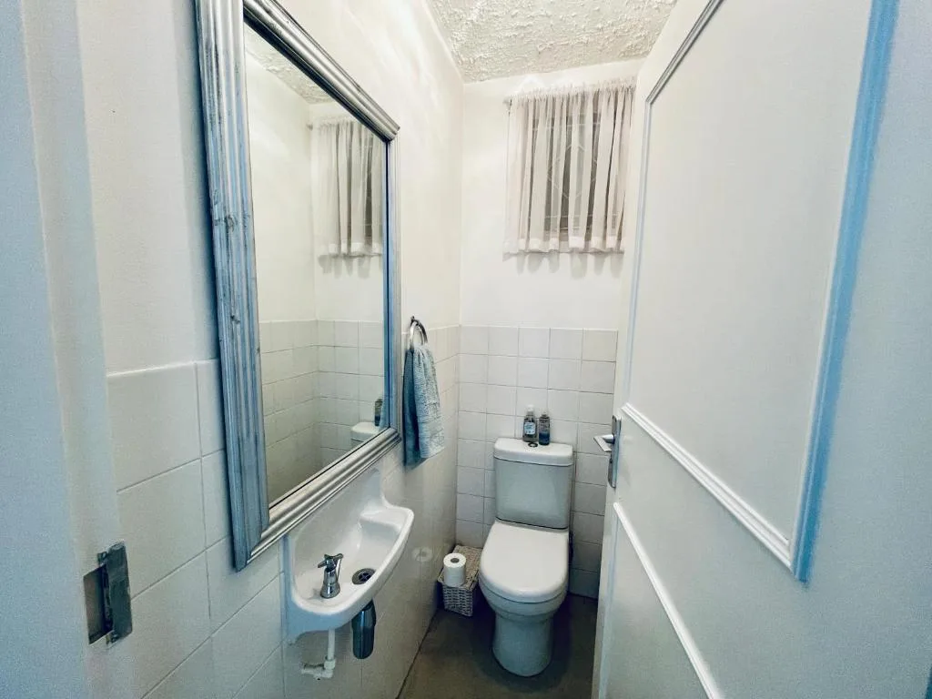 Clean bathroom with toilet, sink, mirror and tiled walls