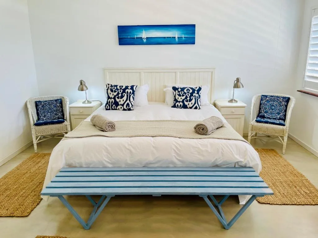 Bright bedroom with cream bed, nautical decor, and blue striped bench