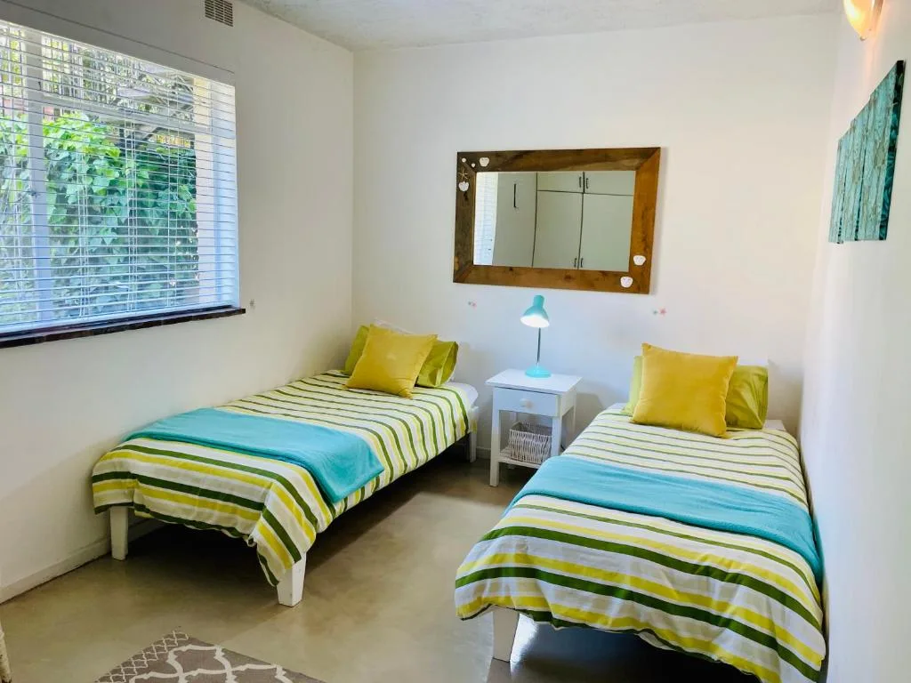 Twin bedroom with colorful striped bedding and bright yellow accent pillows