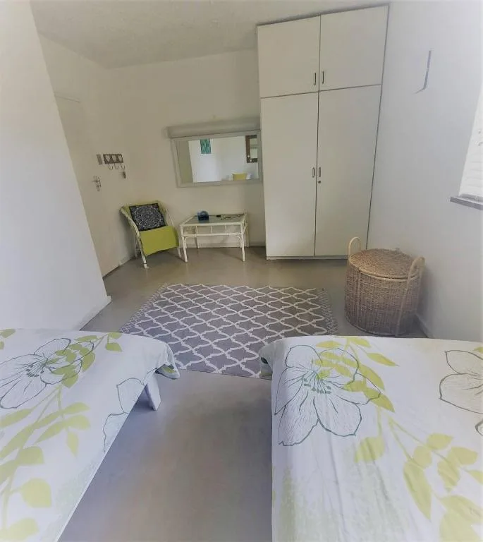 Bright bedroom with floral bedding, wardrobe storage, and sitting area