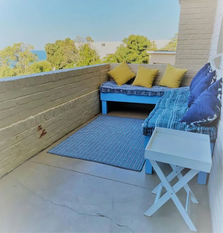 Rooftop deck with blue bench seating, yellow cushions, and ocean views beyond