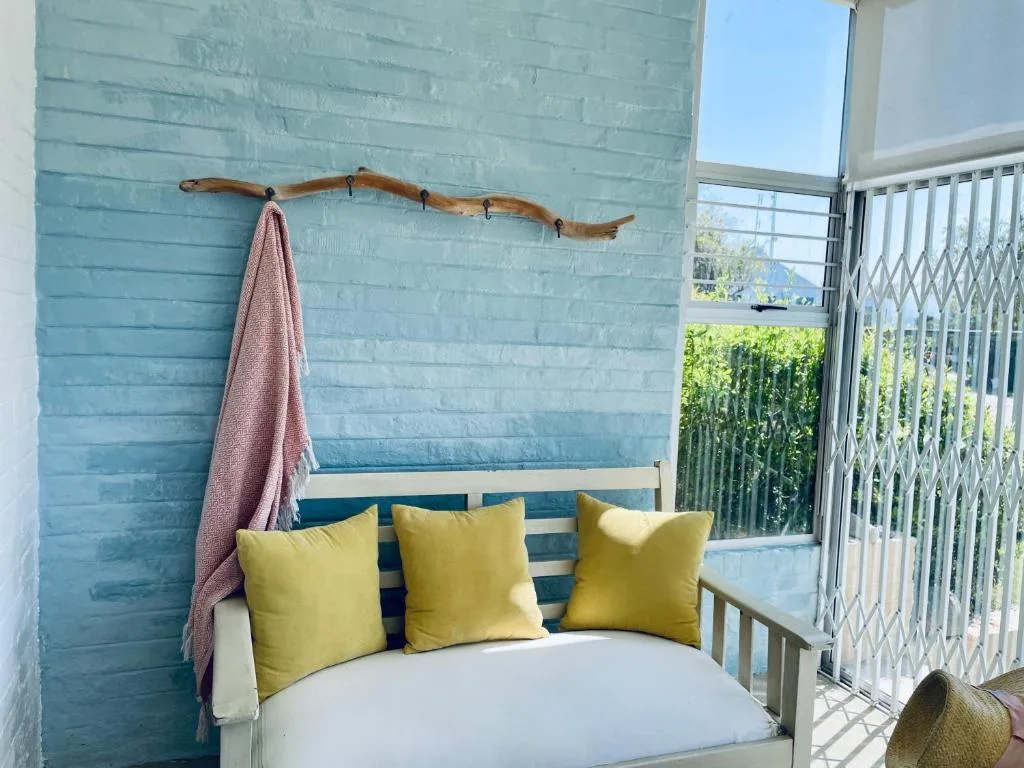 Balcony seating area with yellow cushions and turquoise painted wall